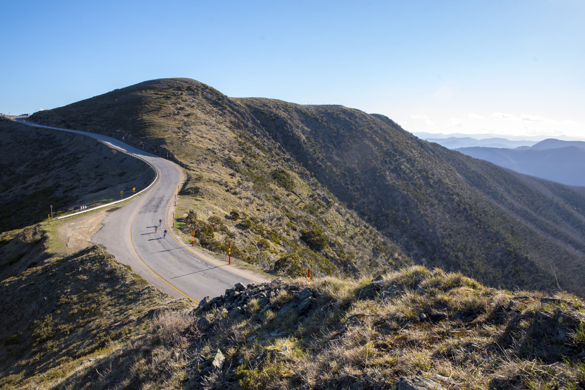 Three cyclists winding down Mt Hotham's alpine roads