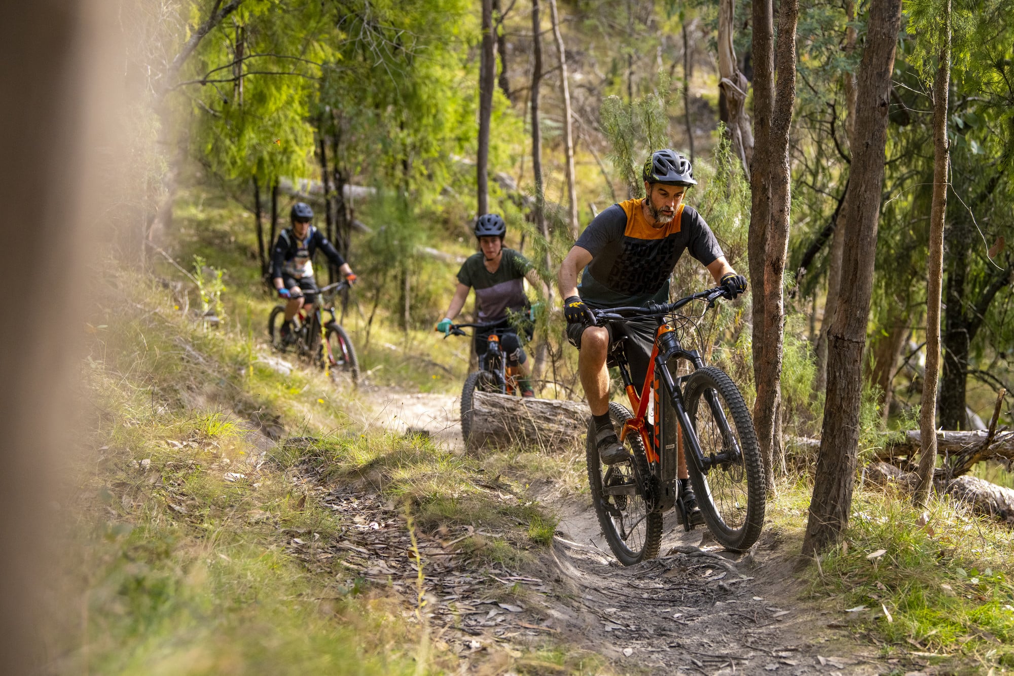 Three cyclists riding through bushland at Big Hill Mountain Bike Park