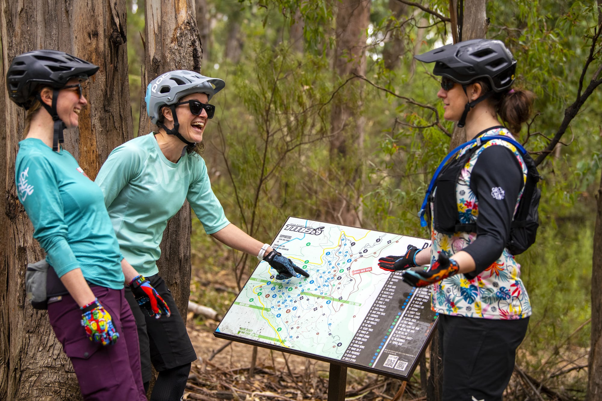 Three cyclists reading the Big Hill Mountain Bike Park trail map in Mount Beauty