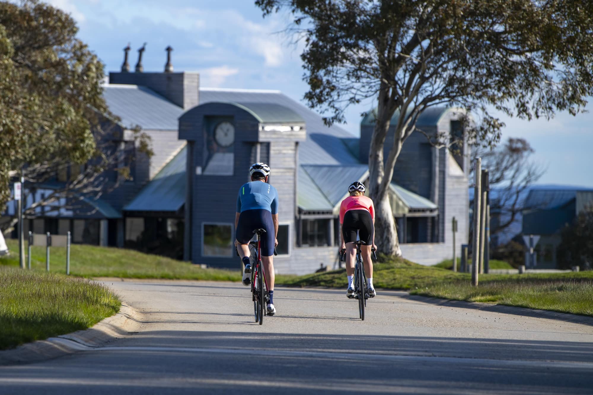 Two cyclists pedalling into Dinner Plain alpine village in summer