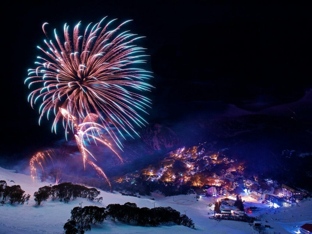 Night time fireworks exploding above the snow covered alpine village of Falls Creek.